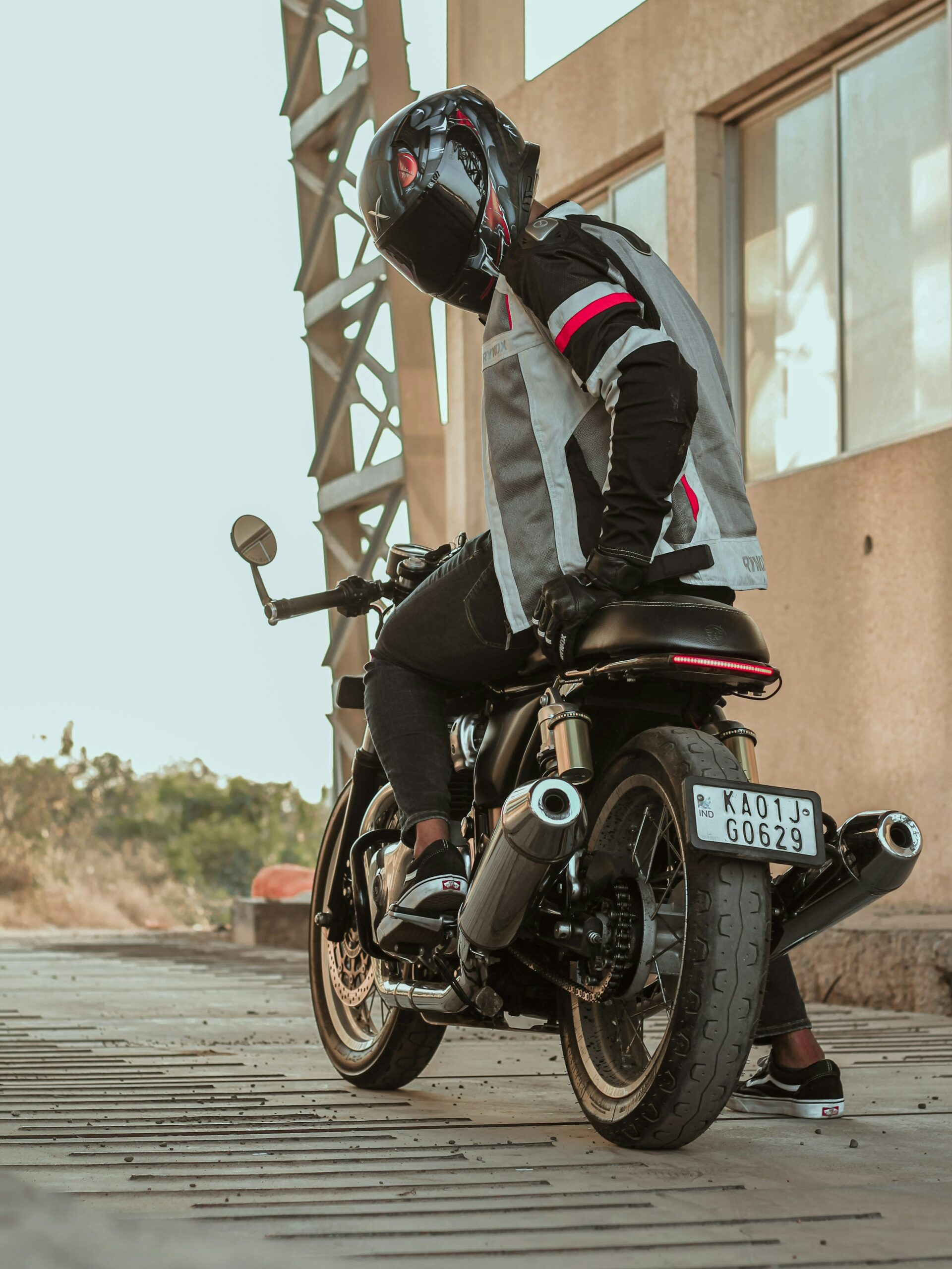 Magasins moto perpignan. Photo d'un motard tout équipé qui se retourne pour montrer l'intégralité de son équipement. Casque, gants, veste, pantalon moto.