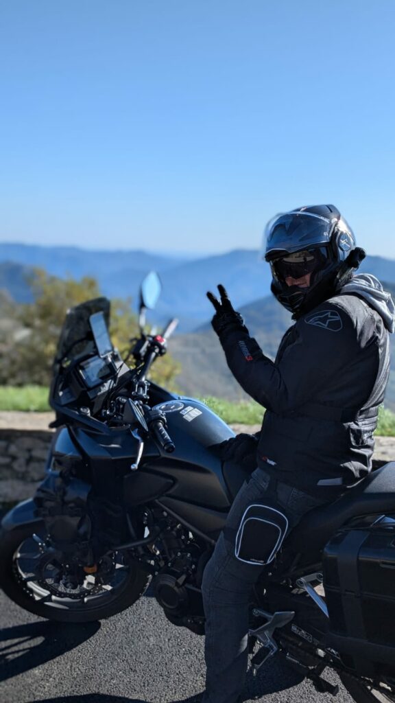 Motard sur sa moto lors d'un arrêt devant un col de montagne faisant un V