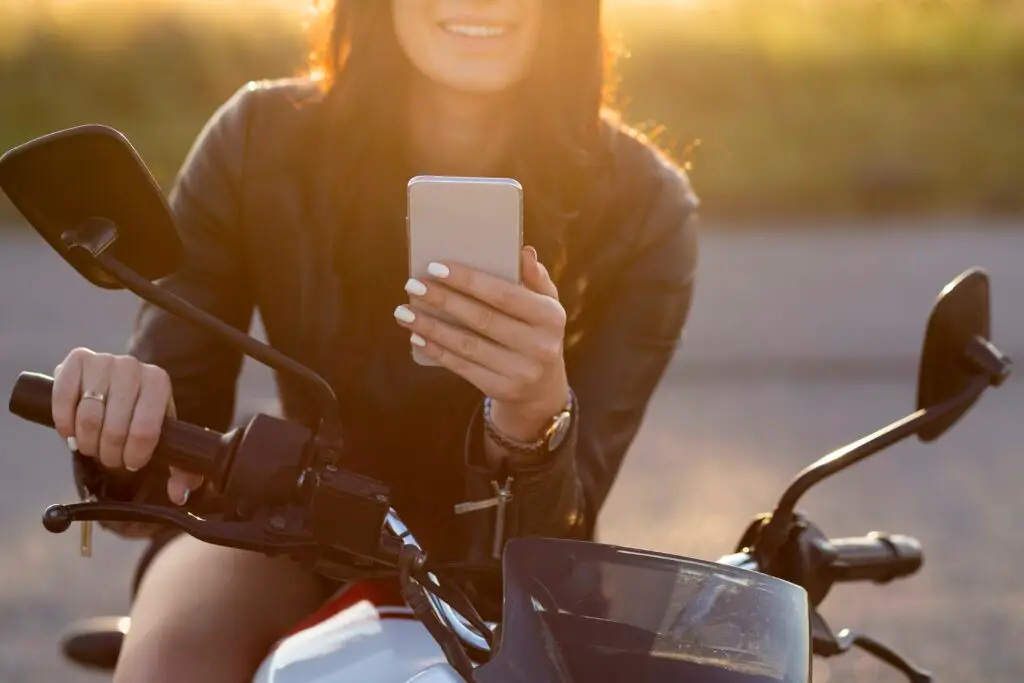 Motarde avec un smartphone à la main en train de regarder ses applications moto